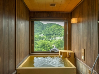 【天然温泉客室ヒバ風呂（渓谷側）】窓から移ろう景色を眺めながら、気の向くままに何度でも湯浴みをお愉しみいただけます。