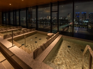 夜、きらめく海とビルの光を眺めながら露天風呂で、日々の疲れをゆったり癒していただけます