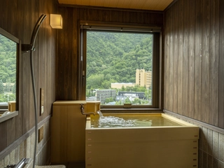 【天然温泉客室ヒバ風呂（国道側）】窓から移ろう景色を眺めながら、気の向くままに何度でも湯浴みをお愉しみいただけます。