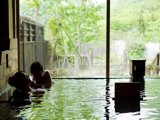【大浴場内湯(寝湯)】開放的な大きな窓からは四季折々の景色をご覧いただけます。
