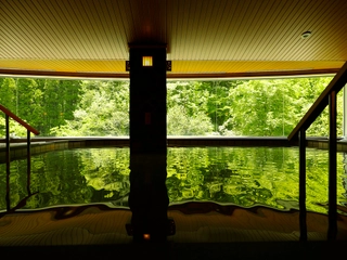 内風呂【大浴場】「山月の湯」内湯…湯量豊富な自家源泉かけ流しの湯を、大自然を望む湯舟でご堪能下さいませ。