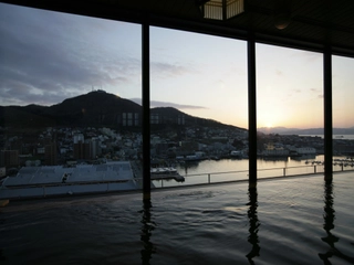 【大浴場/内湯】沈みゆく夕日と函館山のコントラストは貴方の心に感動を覚えさせます。