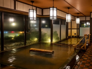 【大浴場/内湯】落ち着いた照明と窓から見える夜景でリラックス。