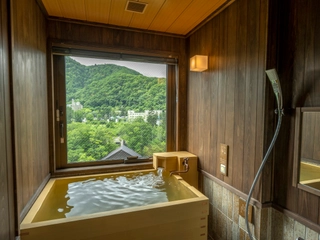 【天然温泉客室ヒバ風呂（渓谷側）】窓から移ろう景色を眺めながら、気の向くままに何度でも湯浴みをお愉しみいただけます。