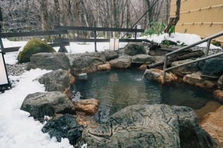 【貸切露天風呂（冬）】しんし んと降る雪を眺めながら湯浴みを堪能いただけます。