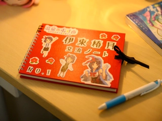 机の上には、勉強していたかのような演出が施されています。椿月ちゃんのイメージカラーの赤いノートが置かれています。