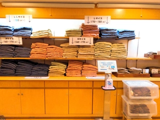 フロント横に館内着コーナーがございます。（ご自身でサイズと色を選んでお部屋へお持ちいただくスタイルです。）